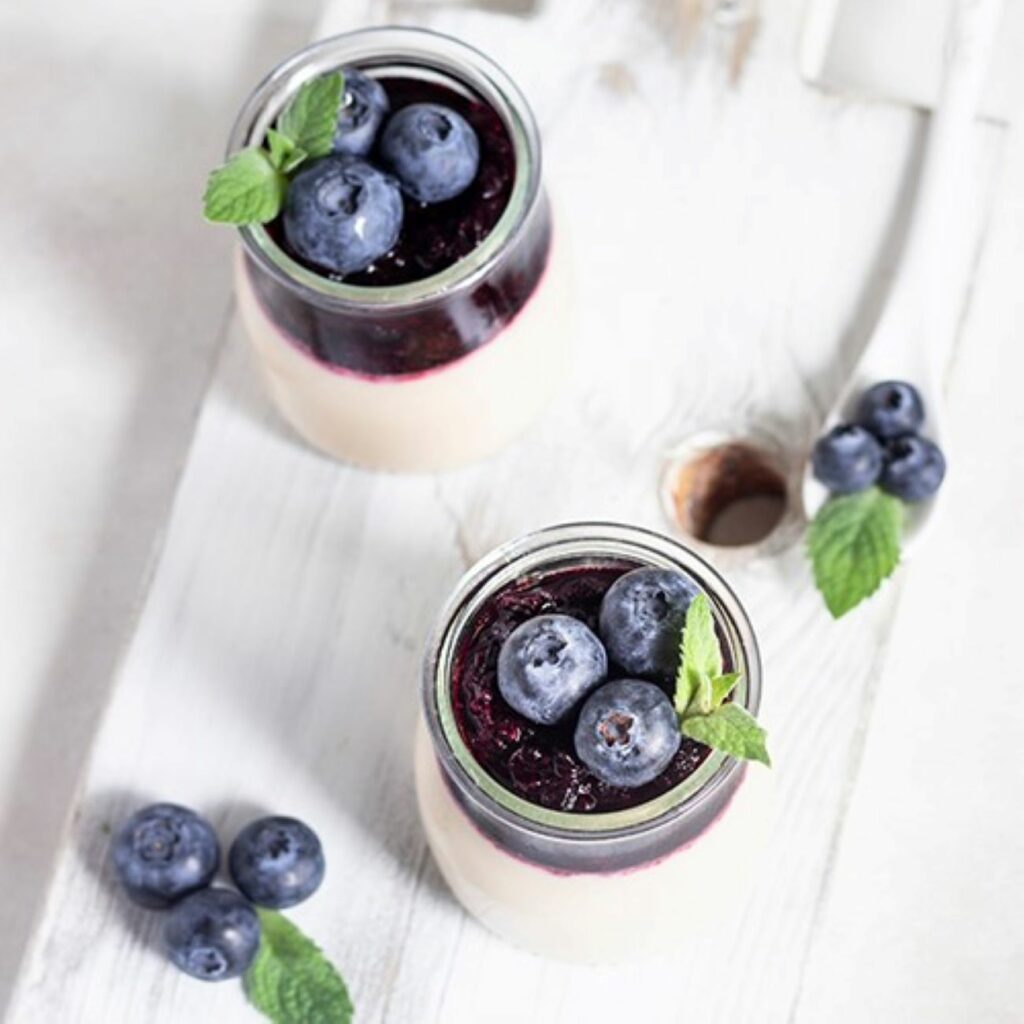 Panna Cotta z puree borówkowym i świeżymi borówkami podaje się w małych szklaneczkach deserowych