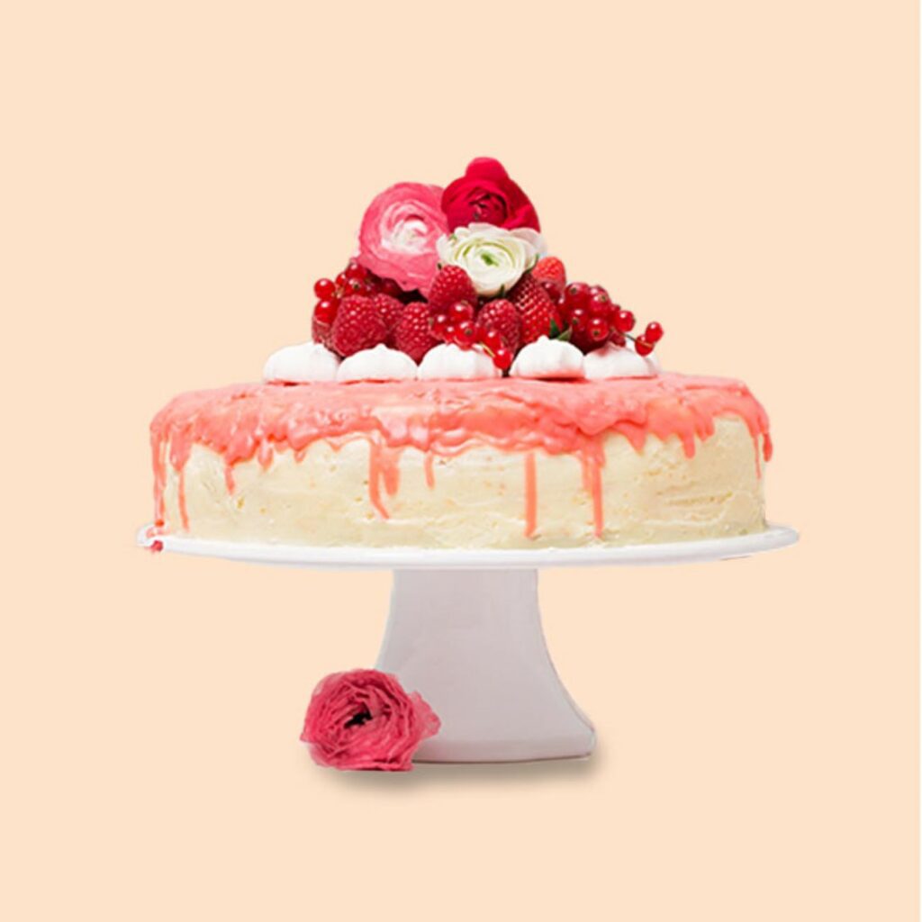 Truskawkowy Drip Cake podawany jest udekorowany na talerzu z ciastem.