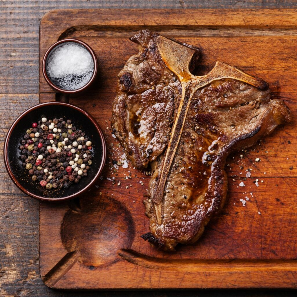 T-Bone-Steak wird auf einem Holzbrett serviert
