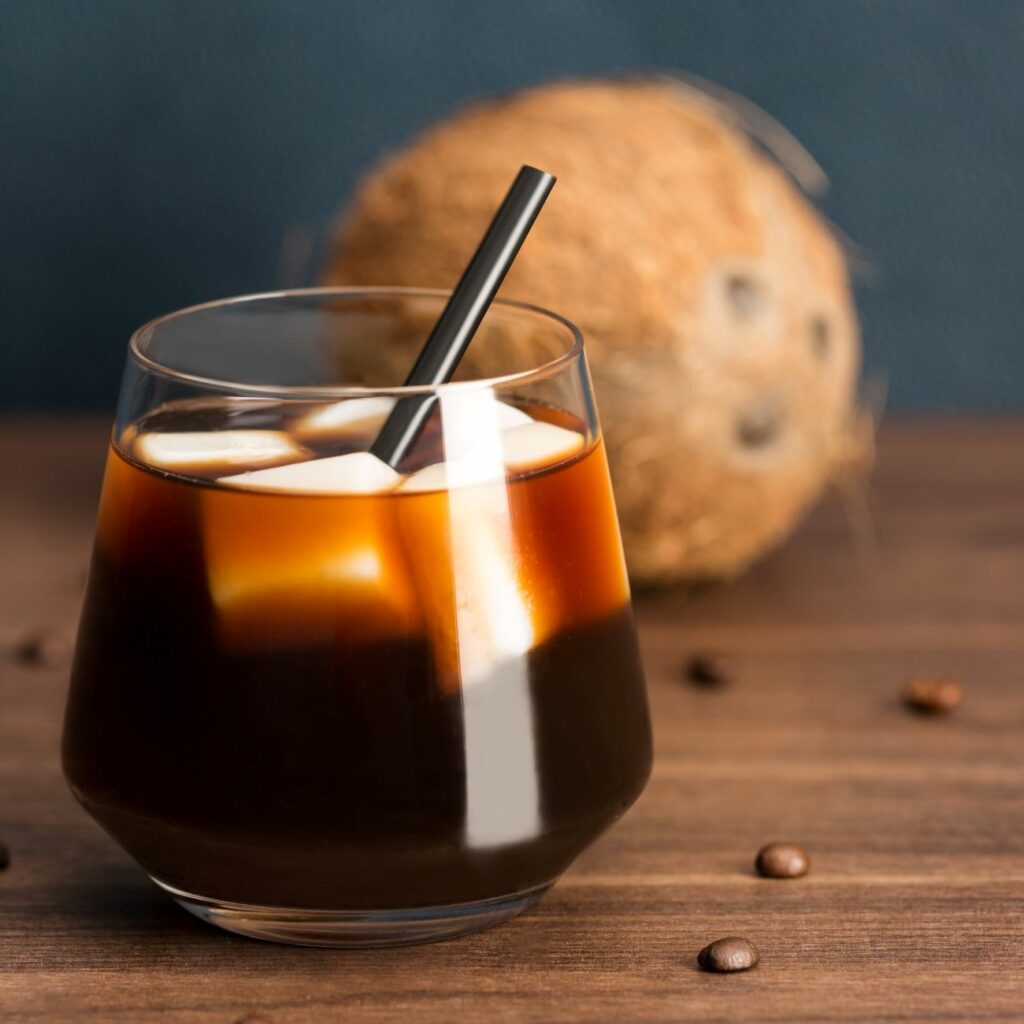 Kawa na lodzie z kostkami lodu z mleka kokosowego podawana jest w szklance ze słomką.