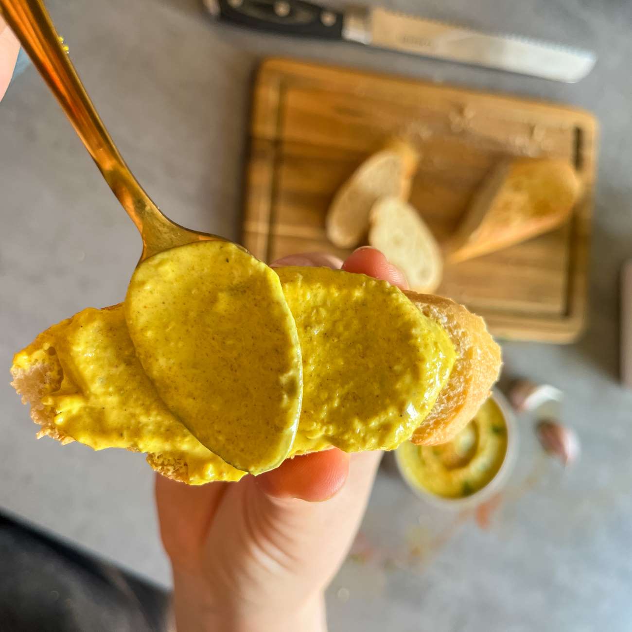 Curry-Dattel-Dip wird mit einem Löffel auf einem Stück Baguette verteilt.