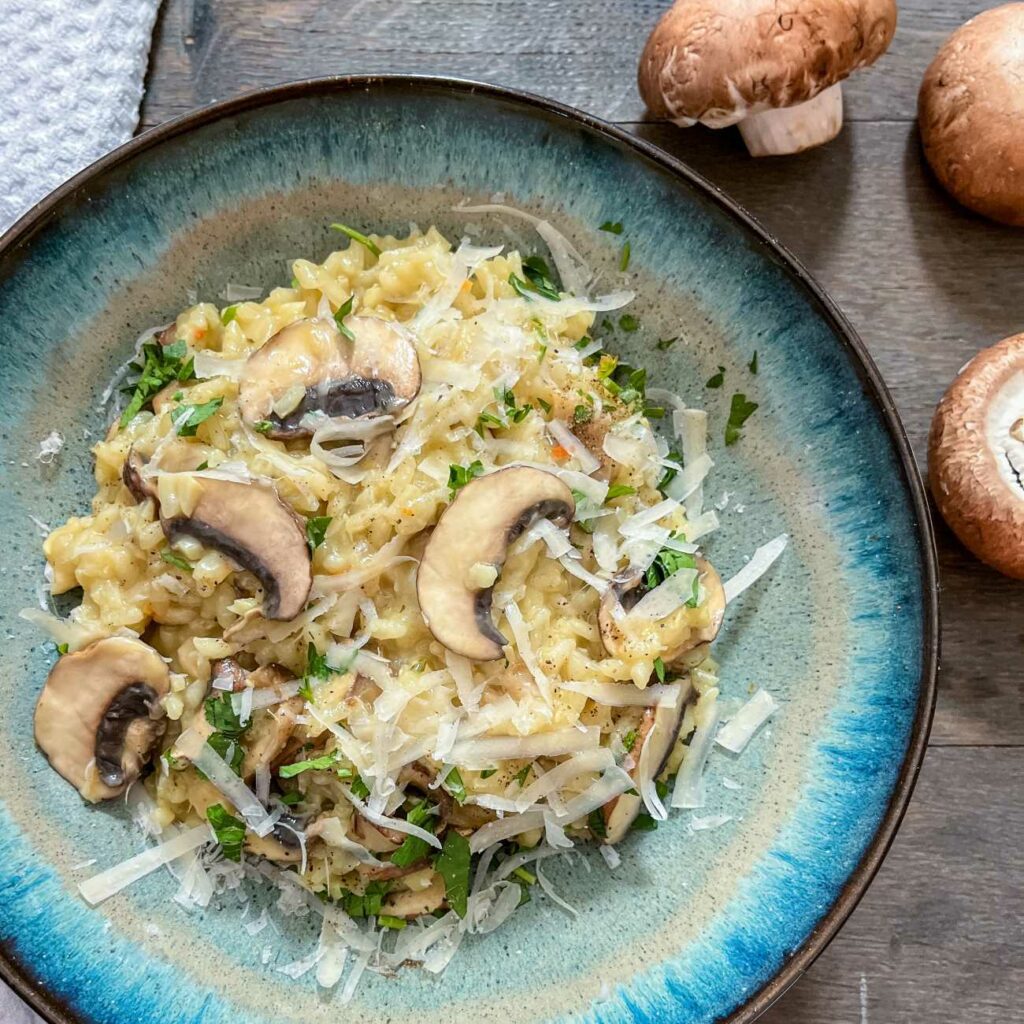 Grzybowe risotto podaje się w głębokim naczyniu z kilkoma grzybami.
