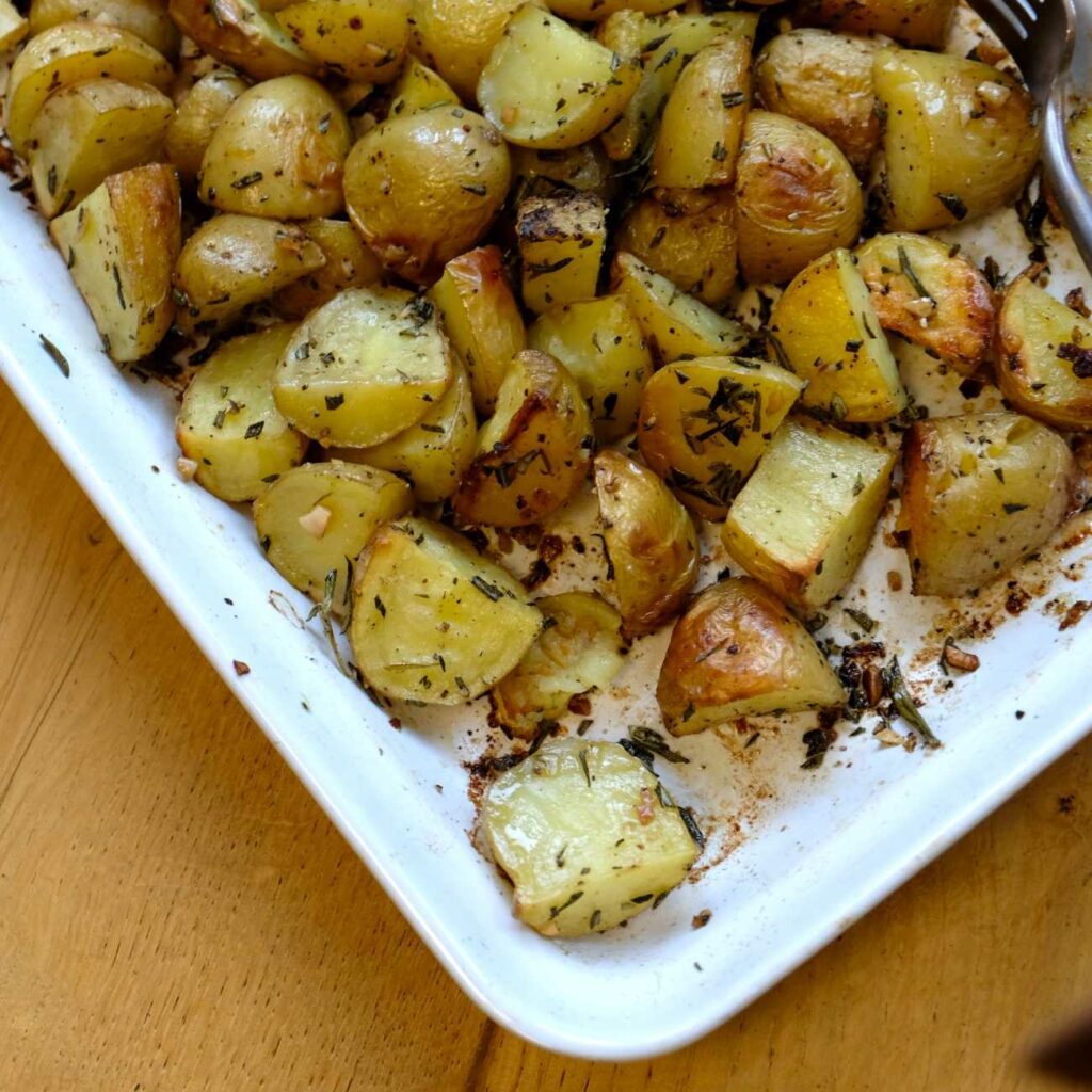 Ziemniaki rozmarynowe są pokazane w białym naczyniu żaroodpornym.
