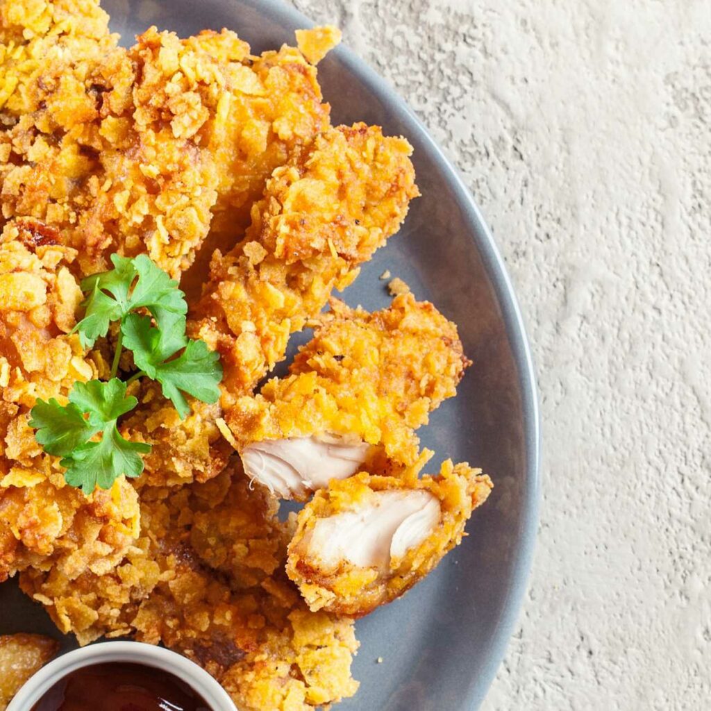 Chicken Nuggets aus der Heißluftfritteuse werden auf einem grauen Teller mit Ketchup serviert.