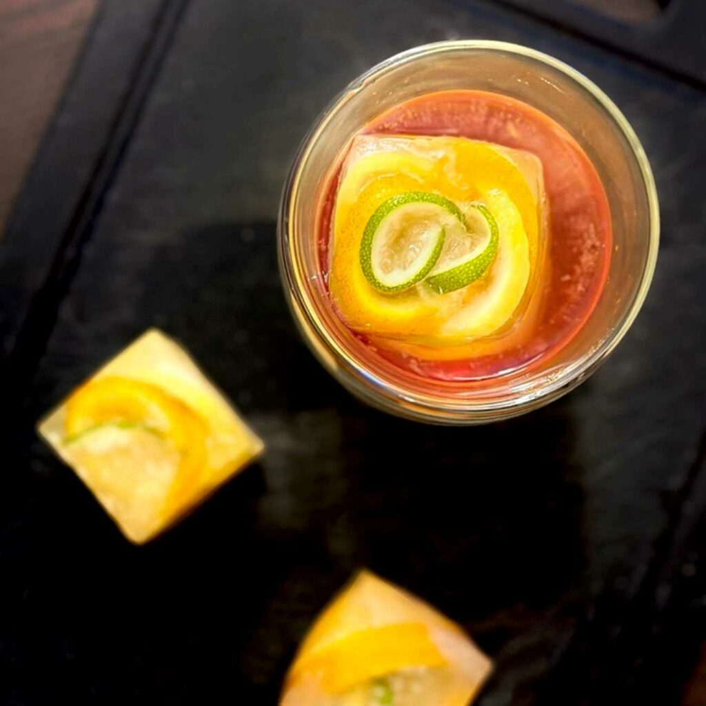 Eiswürfelrosen aus Zitrusfrüchten werden in einem Glas von oben gezeigt.