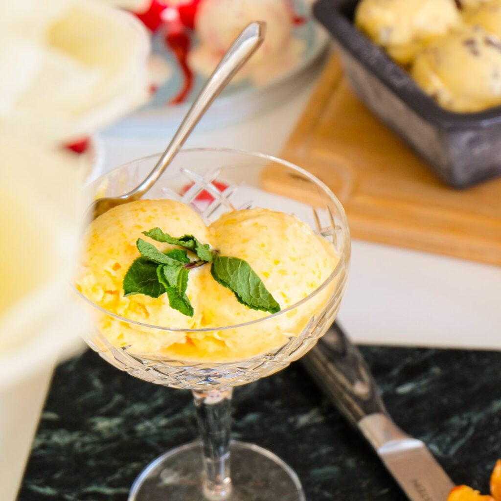 Pfirsicheis wird in einem Glas mit Stiel mit Minze serviert.