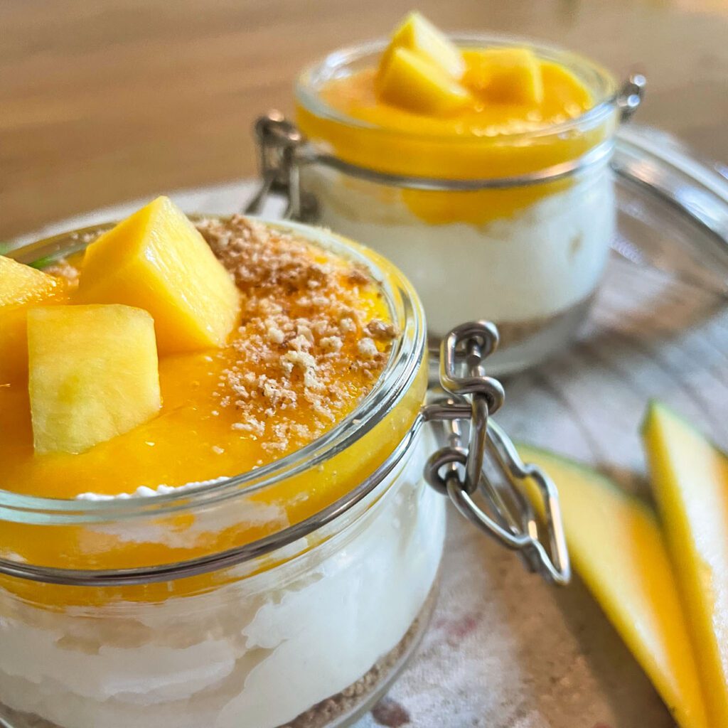 Mango-Dessert im Glas wird mit Minze und Keksen garniert gezeigt.