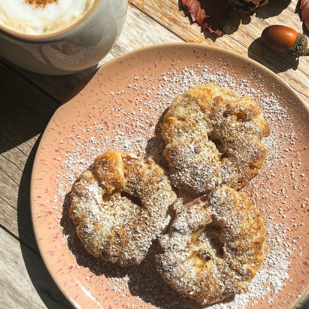 Apfelringe werden auf einem Teller und mit Kaffee in der Sonne serviert.