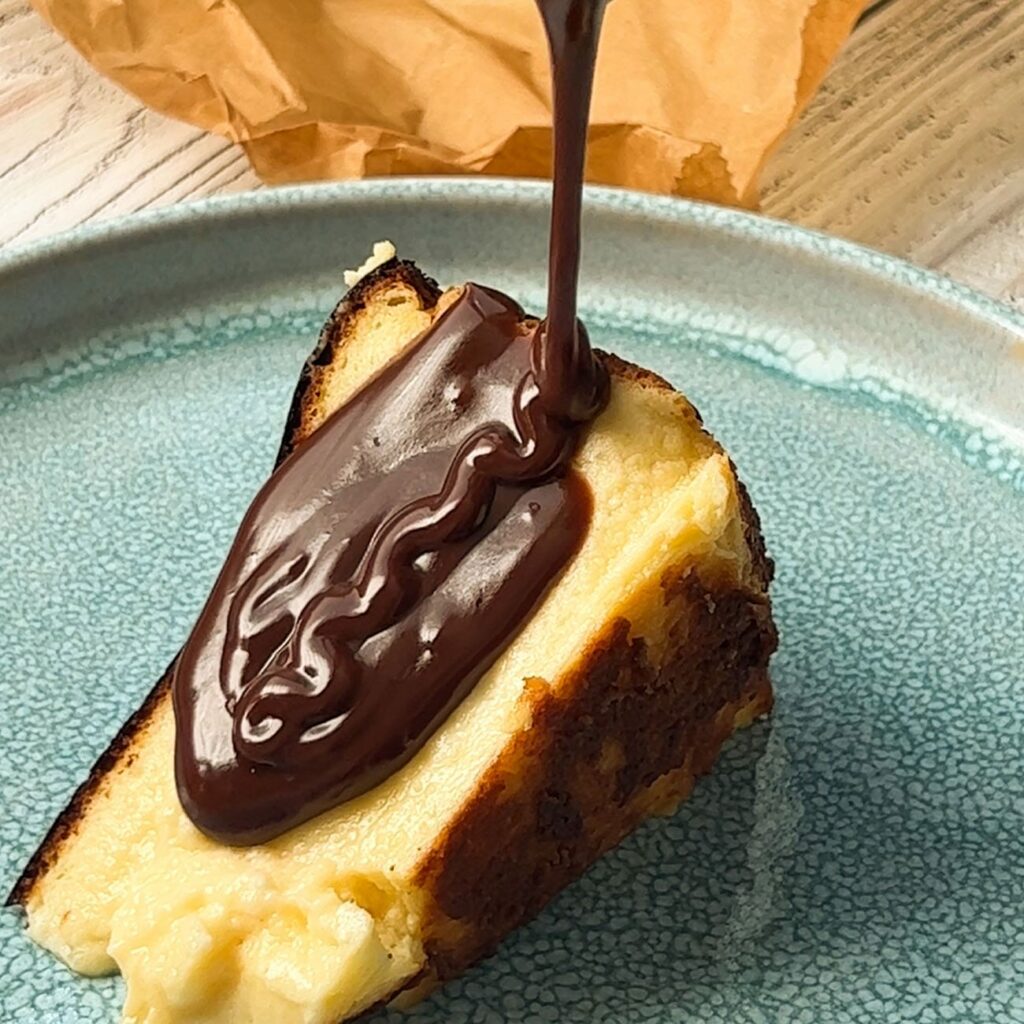Schoko-Sauce wird auf ein Stück Kuchen gegossen