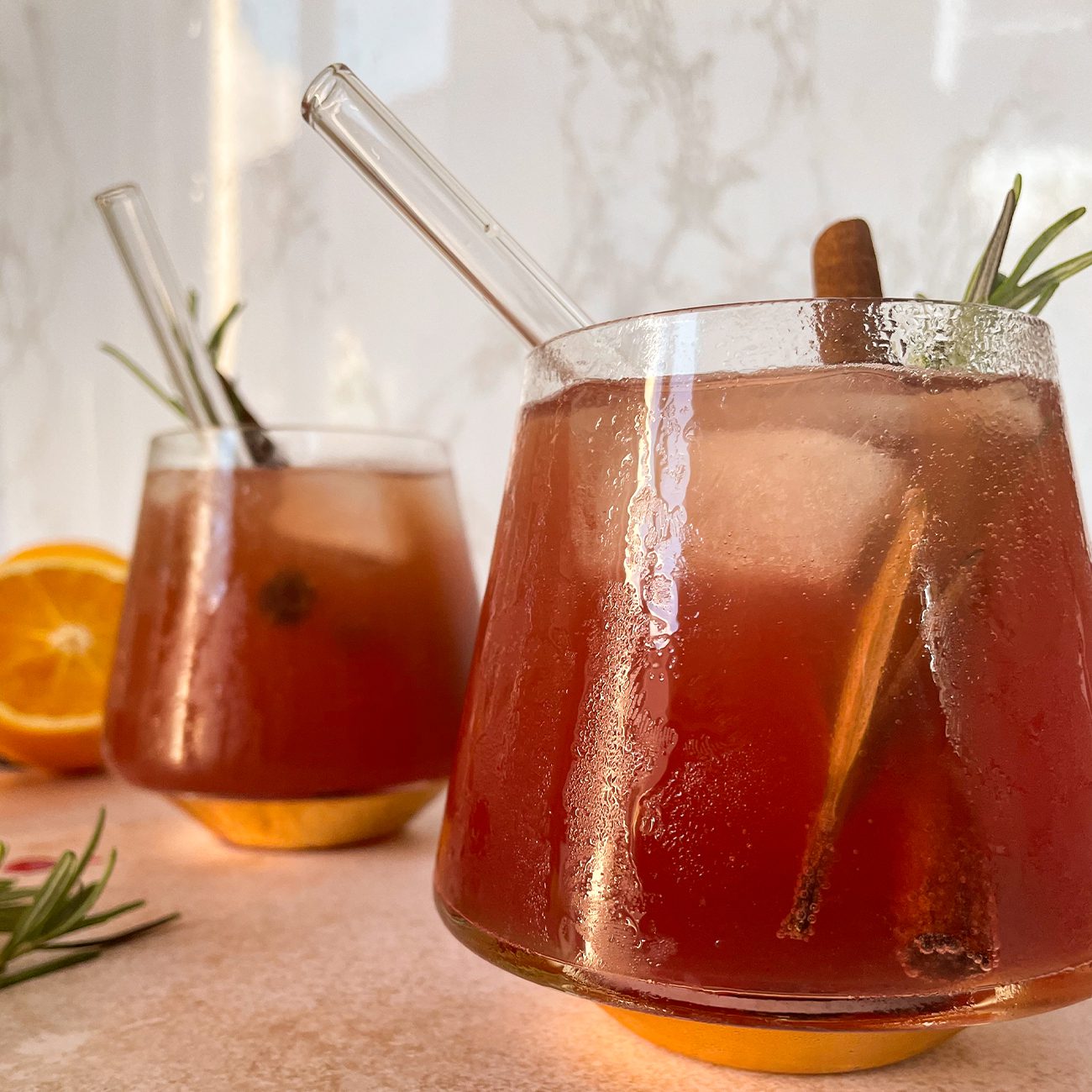 Winter Mocktail wird in zwei Gläsern mit Zimtstangen und Rosmarin serviert.